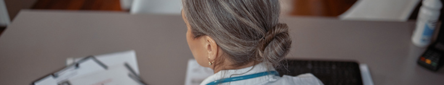 Healthcare provider reviewing patient paperwork at her desk | Amgen By Your Side for BKEMV®